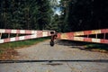 Old gate blocks the road leading to the forest. Protected area, entrance is prohibited, passage is closed. Red-and-white barrier Royalty Free Stock Photo