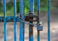 The old gate made from steel reinforeced bars painted in blue locked with the chain and the padlock Royalty Free Stock Photo