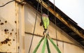 Old girder crane with large iron hook lifts heavy load on slings