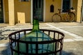 An Old Glass Wine Bottle in the Courtyard with an Old Bicycle Wheel