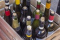 Old glass wine bottles with corks and multi-colored labels in a wooden box close-up Royalty Free Stock Photo