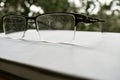 Old glasses with frames on a gray surface against the background of blurred nature Royalty Free Stock Photo