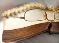 Old glasses lying on a vintage book with a blurred background and beautiful bokeh