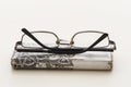 Old glasses resting on a mobile phone with an old and tacky case on a white background that isolates the objects