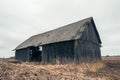 Old gloomy abandoned farm barn and yellow grass field with overcast sky. Royalty Free Stock Photo