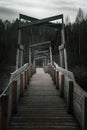 Old and gloomy wooden bridge over the river. Detachment in the water. Gloomy and mysterious forest. Cloudy sky. Royalty Free Stock Photo
