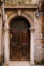 Close-ups of building facades in Venice, Italy. An old, gloomy wooden door, brown. Stone arched doorway. The facade of a Royalty Free Stock Photo