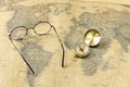 Old gold compass with cover and spectacles on vintage map, macro Royalty Free Stock Photo