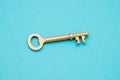 Old gold key isolated on blue background with copy space Royalty Free Stock Photo