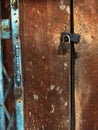 Old gold steel lock and damaged and rusted steel door on wooden door. Locked on wooden door with old steel metal shutter and Royalty Free Stock Photo