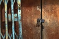 Old gold steel lock and damaged and rusted steel door on wooden door. Locked on wooden door with old steel metal shutter and Royalty Free Stock Photo