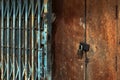 Old gold steel lock and damaged and rusted steel door on wooden door. Locked on wooden door with old steel metal shutter and Royalty Free Stock Photo