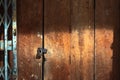 Old gold steel lock and damaged and rusted steel door on wooden door. Locked on wooden door with old steel metal shutter and Royalty Free Stock Photo