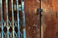 Old gold steel lock and damaged and rusted steel door on wooden door. Locked on wooden door with old steel metal shutter and Royalty Free Stock Photo