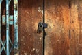 Old gold steel lock and damaged and rusted steel door on wooden door. Locked on wooden door with old steel metal shutter and Royalty Free Stock Photo