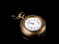 Old golden pocket watch on a black reflective surface Royalty Free Stock Photo