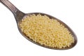 In the old golden spoon there is a small pile of food - wheat grain dried couscous isolated macro