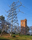 Old gothic tower sits behind modern electricity pylon