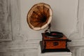 Old gramophone with horn speaker stands against anicent background, produces songs recorded on plate. Music and nostalgia concept.