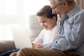 Old granddad and small grandson with laptop on couch