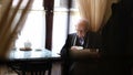 Old grandfather reads the press while sitting in a cafe. The pensioner is resting
