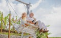 Old grandfather and young child grandson swinging in garden outdoors. Grand dad and grandson sitting on swing in park