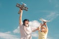 Old grandfather and young child grandson with toy jetpack plane and quadcopter drone against sky. Child pilot aviator