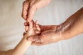 Old grandmother hands holding newborn hand, fourth generation family life. the concept of a family and a new life into a selective Royalty Free Stock Photo