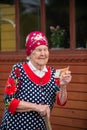 Old grandmother incredulously examines a 5-thousandth bill at the porch of her wooden house