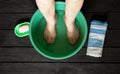 the old grandmother's feet are washed in a plastic bowl with water and soap on the black floor, towels were brought, the