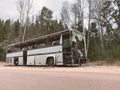 Broken bus abandoned in countryside. Old forgotten gray bus on the road in woods. landscape with shattered bus by the roadside