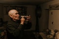 Old man drinks wine from a glass bottle in the dark basement Royalty Free Stock Photo
