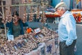 An old gray-haired man trades with a seller of garlic and spices