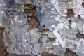 old gray heavily damaged concrete wall with deep relief and protruding red bricks, cracks and various stains of paint. rough Royalty Free Stock Photo