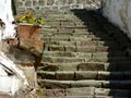quaint old uneven stone exterior stair with shadows. weathered grunge white stucco exterior walls Royalty Free Stock Photo
