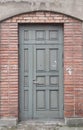 Old gray wooden door in red brick wall, empty abstract interior, vertical background texture Royalty Free Stock Photo