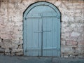 Old gray wooden double door in an ancient authentic stone wall. Gothic style Fortress. Stone medieval buildings Royalty Free Stock Photo