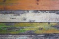 Old gray wooden wall fence of multi-colored boards with peeling white, green and red paint. horizontal lines. rough surface Royalty Free Stock Photo