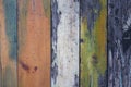 Old gray wooden wall fence of multi-colored boards with peeling white, green and red paint. vertical lines. rough surface texture Royalty Free Stock Photo