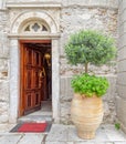 An old Greek orthodox church natural wood door on stone wall and potted plant. Royalty Free Stock Photo