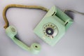 Old green antique rotary telephone with removed receiver on blue background. Vintage landline home phone with dial Royalty Free Stock Photo