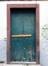 Old green closed wooden door locked and barred shut with nails with peeling paint and a red surround in a white wall Royalty Free Stock Photo