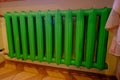 Old green color cast iron radiator heating on a background of an orange wall. Royalty Free Stock Photo