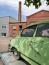 Old and green crashed car being taken for repairing on a truck