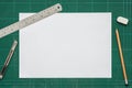 Old green dirty cutting mat, with empty white paper A4 size, stainless steel ruler, cutter knife, pencil and eraser, top view of Royalty Free Stock Photo