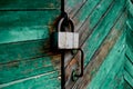 Old green door or wall of a wooden house in rustic style, with peeling paint.On the door hangs an old metal lock Royalty Free Stock Photo