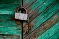 Old green door or wall of a wooden house in rustic style, with peeling paint.On the door hangs an old metal lock Royalty Free Stock Photo