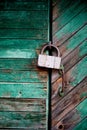 Old green door or wall of a wooden house in rustic style, with peeling paint.On the door hangs an old metal lock Royalty Free Stock Photo