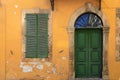 Old green door and window of ancient yellow building Royalty Free Stock Photo