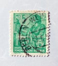 An old green east german postage stamp with a design of a female boat captain
